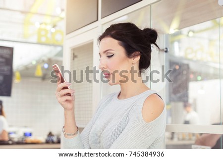 Woman typing write message on smart phone in a modern cafe.