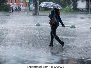 Woman With Umbrella Going On Street During Heavy Rain .