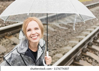 A woman under a transparent umbrella on a railway track. - Shutterstock ID 1176774307