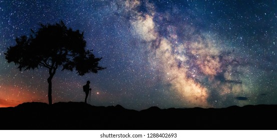 Woman Under Tree Looking At The Stars And Milky Way. Scenery Landscape With Night Starry Sky And Silhouette Of Standing Woman. Milky Way Galaxy With Traveler. Universe.