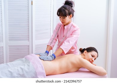 Woman undergoing back massage procedure. Micro-sensory electric microcurrent procedure bio ems for electrode stimulation of face and body with conductive gloves. Anti-wrinkle and anti-aging lifting.