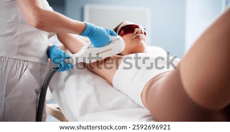 Woman undergoing laser hair removal treatment for smooth underarms. Beautician. Spa.