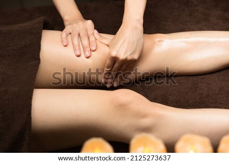 The woman is undergoing an oil massage on her thighs.