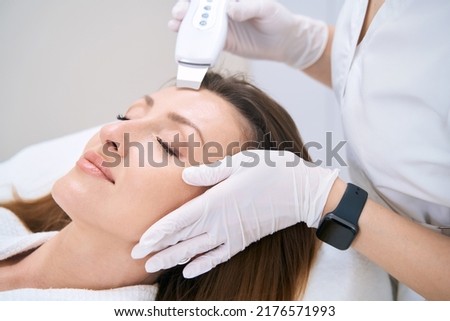Woman is undergoing ultrasonic facial cleaning procedure
