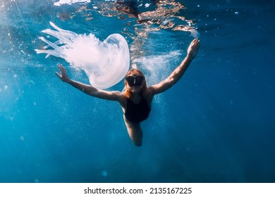 Woman underwater with jellyfish in blue ocean. Lady glides underwater in transparent sea - Shutterstock ID 2135167225