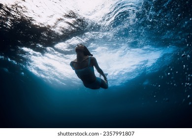 Woman underwater with ocean wave and sun light. Active vacations in ocean - Powered by Shutterstock