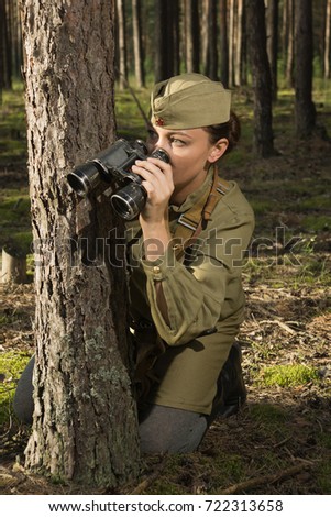 Woman in uniform of the Red Army of the Second World War. She watches through binoculars and scouts.