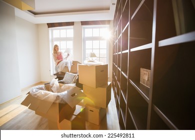 Woman Unpacking Lamp From Moving Box At New House