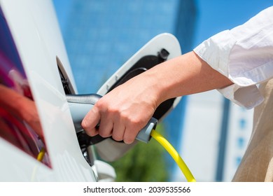 Woman Unplugging The Electric Car Charger At A Downtown Charging Point