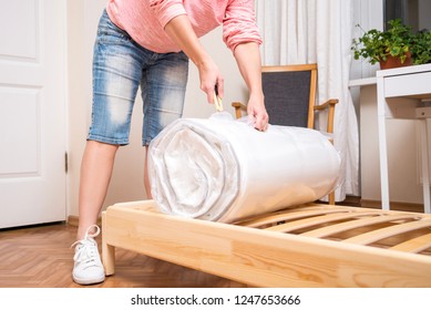 Woman unrolling new Mattress, cutting vacuum package - Powered by Shutterstock