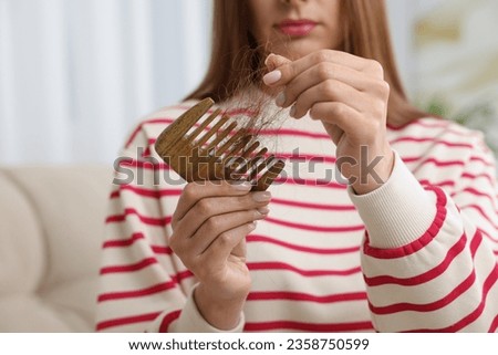 Woman untangling her lost hair from comb at home, closeup. Alopecia problem