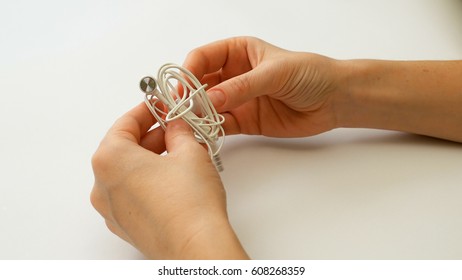 Woman Untangling Tangled Earbuds Or Earphone Knot With Hands