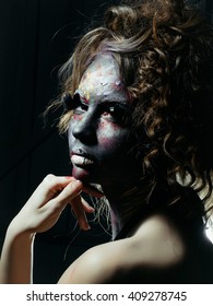 Woman with unusual paint make-up and curly hair in studio
