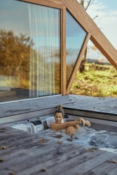 Woman Unwinding In A Hot Tub At A Modern Cabin With Scenic Views