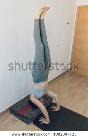 Woman upside down doing yoga at home