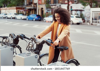 woman in urban station with electric bicycles for rent and commuting around the city to work leading a healthy lifestyle