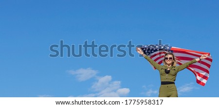 Woman with USA flag against blue sky background. Freedom concept. America Independence Day.