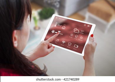 Woman use application for smart home control on tablet. Interior of living room in the background. - Powered by Shutterstock