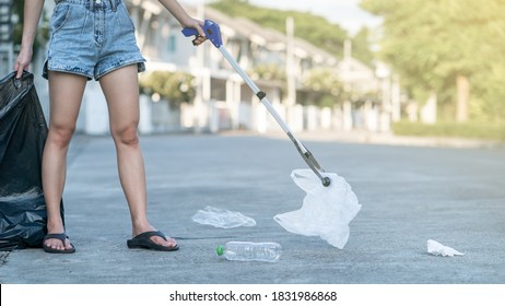 Woman Use Garbage Collector Equipment Keeping Plastic Waste Into Black Bag On Ground.