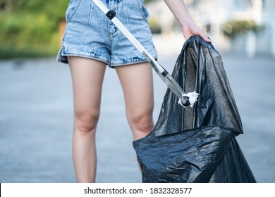 Woman Use Garbage Collector Equipment Keeping Plastic Waste Into Black Bag On Ground.