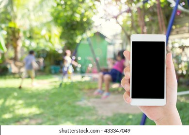 Woman Use Mobile Phone And Blurred Image Of Children In The Playground