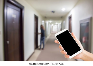 Woman Use Mobile Phone And Blurred Image Of Hotel Corridor With A Woman Try To Open The Door