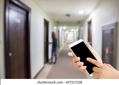 Woman Use Mobile Phone And Blurred Image Of Hotel Corridor With A Woman Try To Open The Door