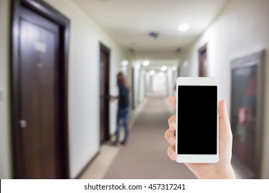 Woman Use Mobile Phone And Blurred Image Of Hotel Corridor With A Woman Try To Open The Door