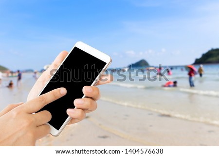 woman use mobile phone and blurred image of people on the beach