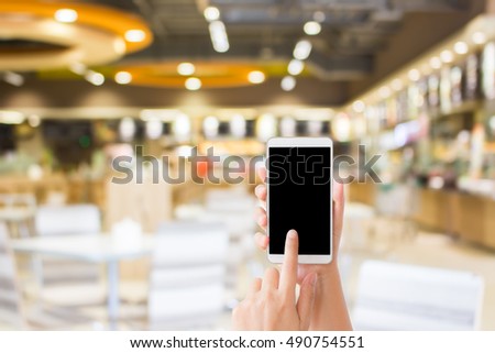 woman use mobile phone and blurred image of food court in the mall as background