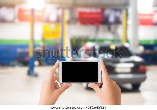 woman use mobile phone and blurred image of the\
automobile repair shop