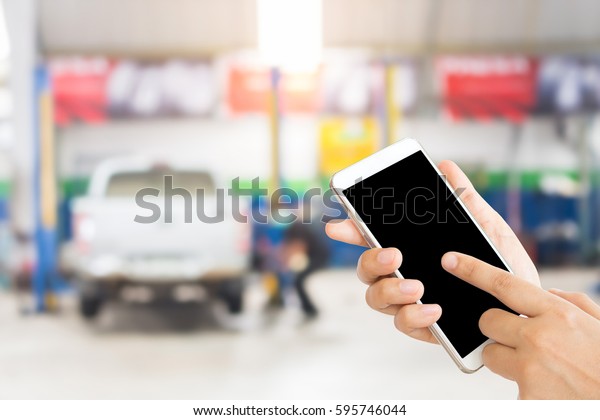 woman use mobile phone and blurred image of the\
automobile repair shop