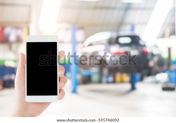 woman use mobile phone and blurred image of the
automobile repair shop