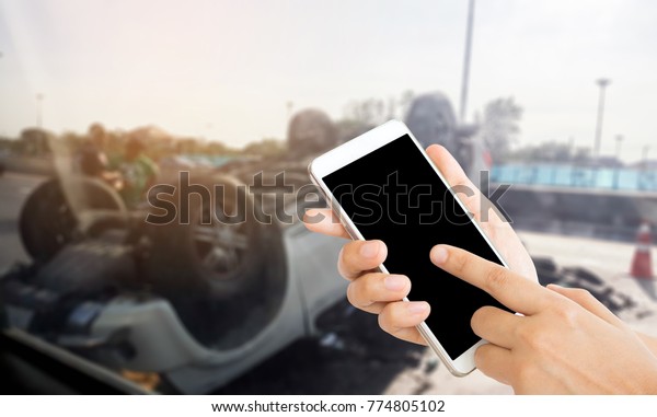 woman use mobile phone and\
blurred image of the accident on the road and the car flipped\
upside down