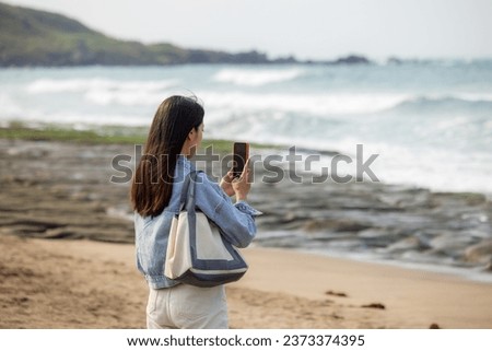 Woman use mobile phone to take photo on beach