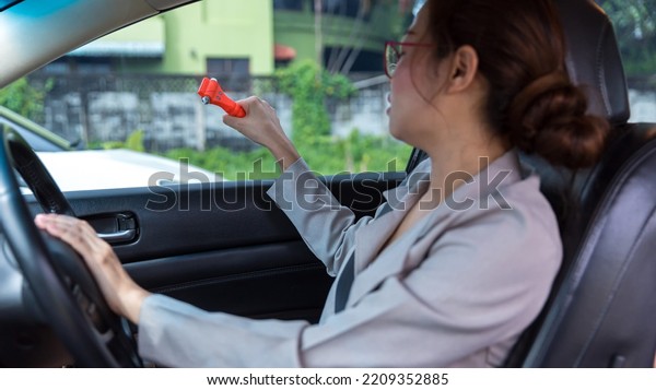 Woman use Safety Hammer and Seatbelt\
Cutter in Cars, break glass When emergency. In case of emergency on\
car safety red hammers to break the grass\
window.