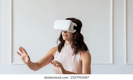 Woman use VR headset exploring virtual reality. Woman immersed in VR, interacting with virtual reality environment. VR technology experience. Woman experience VR technology in modern room - Powered by Shutterstock