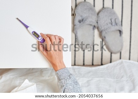 A woman uses a basal thermometer to find out her temperature