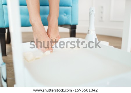 Woman uses a foot bath with white rose petals