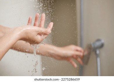 A woman uses hand to measure the water temperature from a water heater before taking a shower