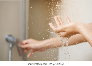 A woman uses hand to measure the water temperature from a water heater before taking a shower	