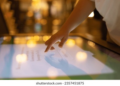 A woman uses an interactive touch screen display at a trade show, searching for information. The concept of education, entertainment and technology - Shutterstock ID 2357451875
