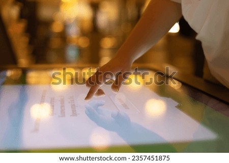 A woman uses an interactive touch screen display at a trade show, searching for information. The concept of education, entertainment and technology