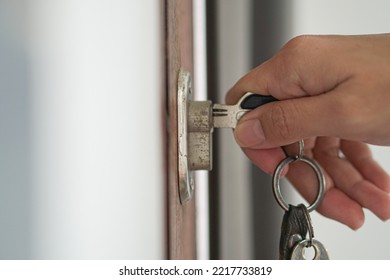 A woman uses a key to unlock the front door.