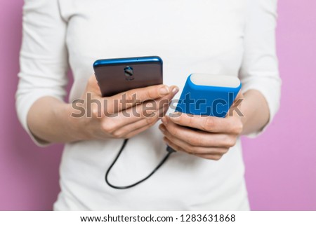 The woman uses a mobile phone, a smartphone, charged from the power bank.