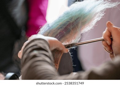 A woman uses a modern metal tool for carding and combing colorful wool fibers on a round rough card. The textile materials are handcrafted. The combs are brown and circular for pulling the fabric. - Powered by Shutterstock