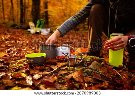 Woman uses portable gas heater and pan for cooking outdoors