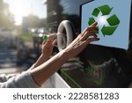 Woman uses a self service machine to receive used plastic bottles and cans on a city street