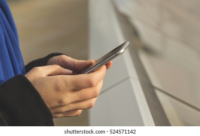 Woman uses smart phone outdoors - Shutterstock ID 524571142