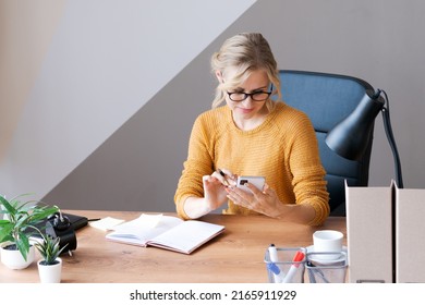 Woman uses smartphone in office. A beautiful girl is looking at mobile phone. Entrepreneur businessman, freelancer, sits at his desk in a yellow jacket. Business, technology concept